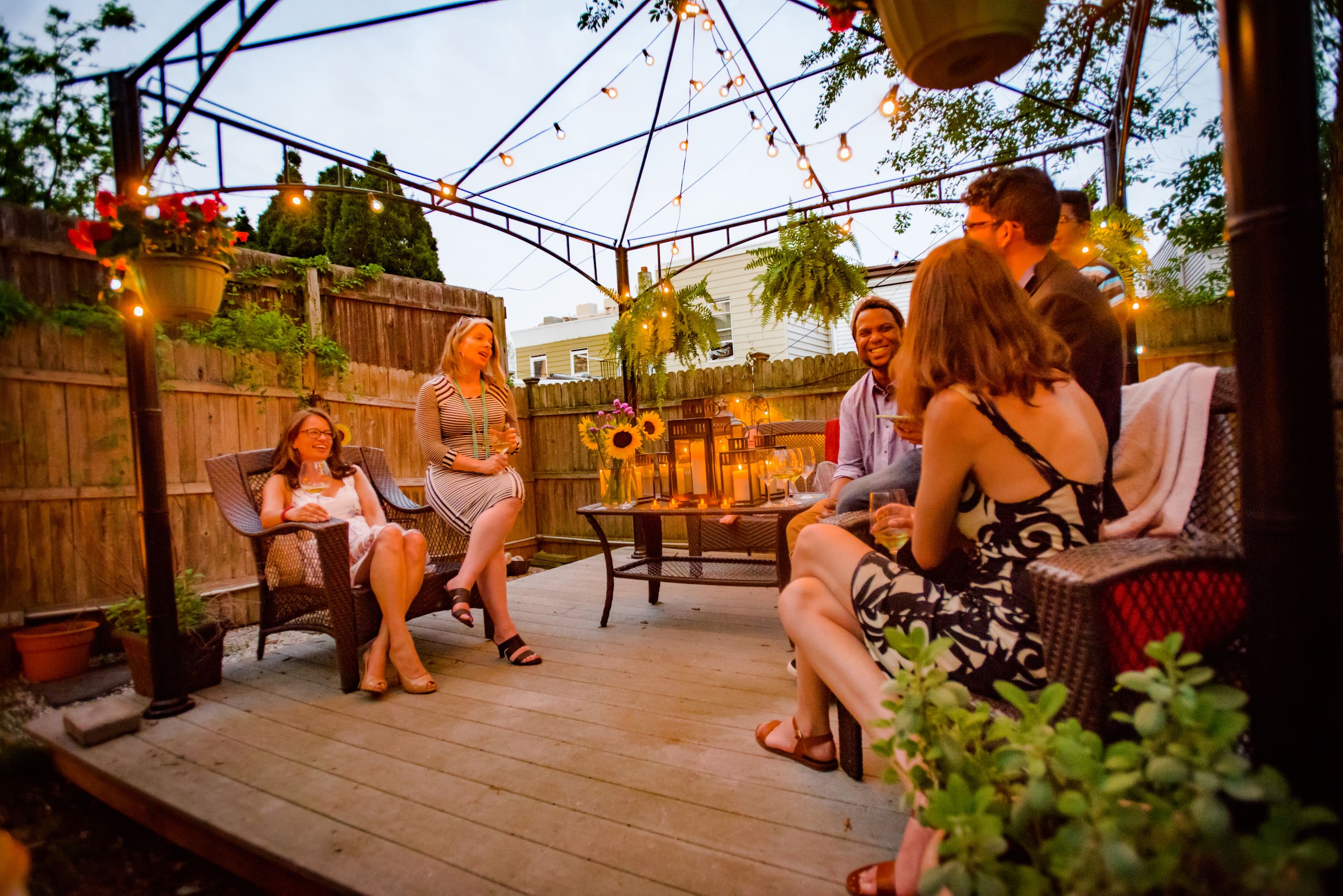 Several people sitting under a pergola in the summer