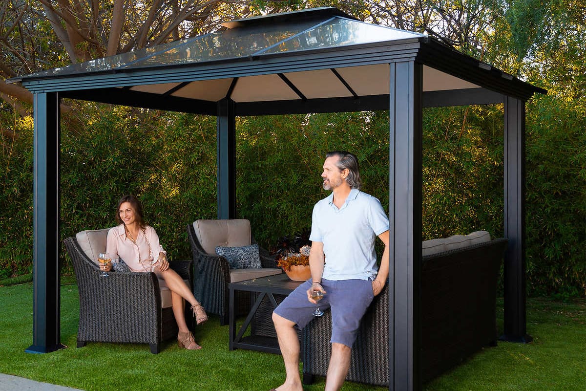 Two people sitting on outdoor seating under gazebo