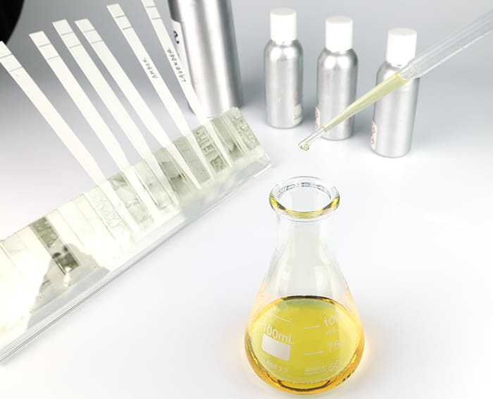 Multiple single note fragrance bottles and test strips with beaker and pipette.