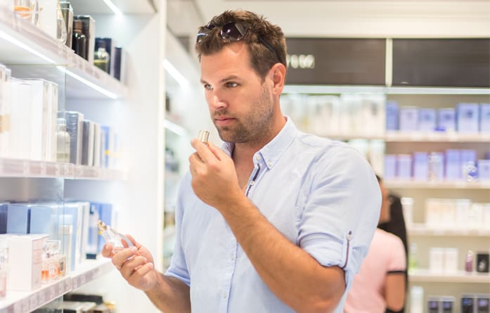 Man shopping in a fragrance department and smelling fragrances from different bottles.