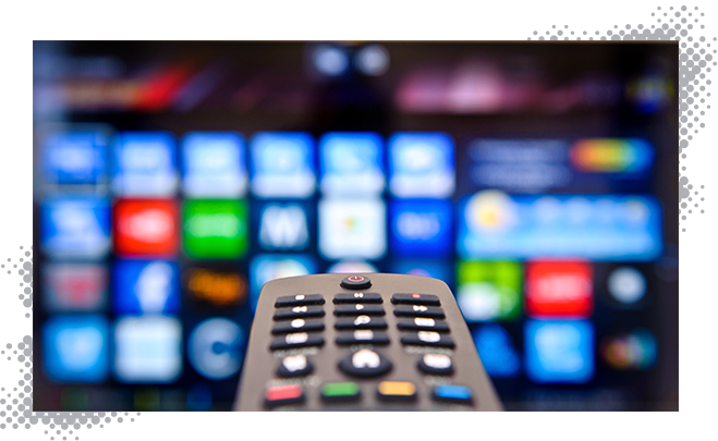 Gros plan sur la télécommande du téléviseur avec plusieurs options de chaînes sur un téléviseur en arrière-plan.