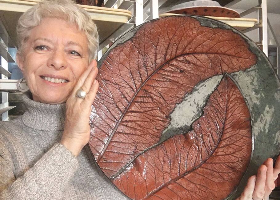 Potter Judy Tait with a plate featuring a unique leaf design