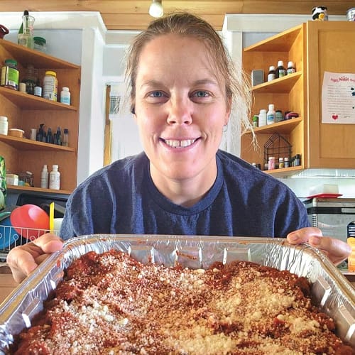 a woman holding a pan of lasagna