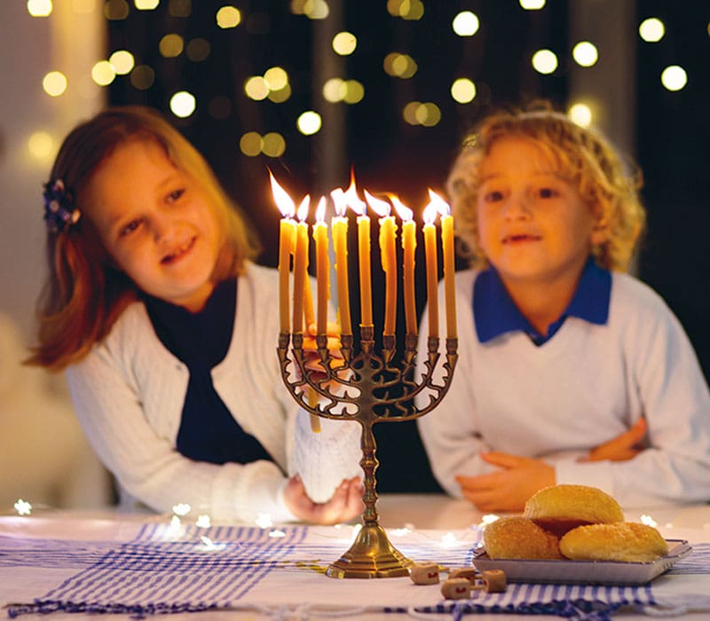 two kids looking at a menorah candle