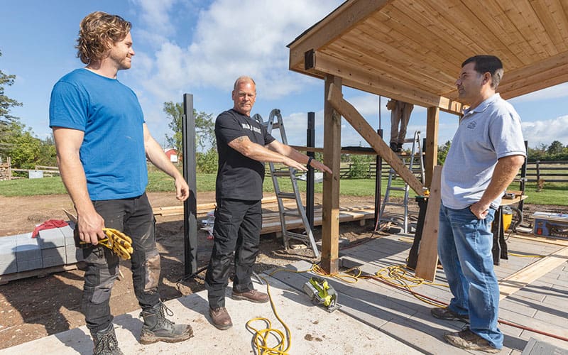 Mike Holmes (centre) with his son, Michael (left), and Vic Maia of Shed Village on the set of Holmes Family Rescue in 2021