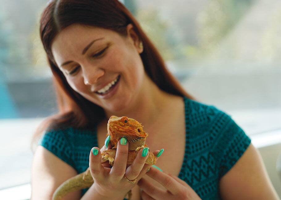 woman holding an iguana