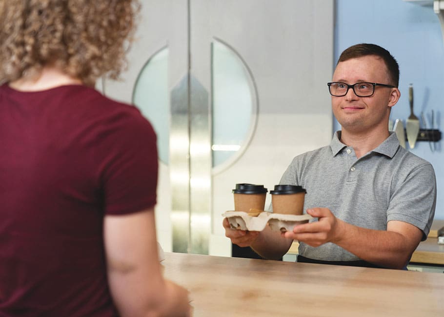 man with down syndrome handing coffee to a customer