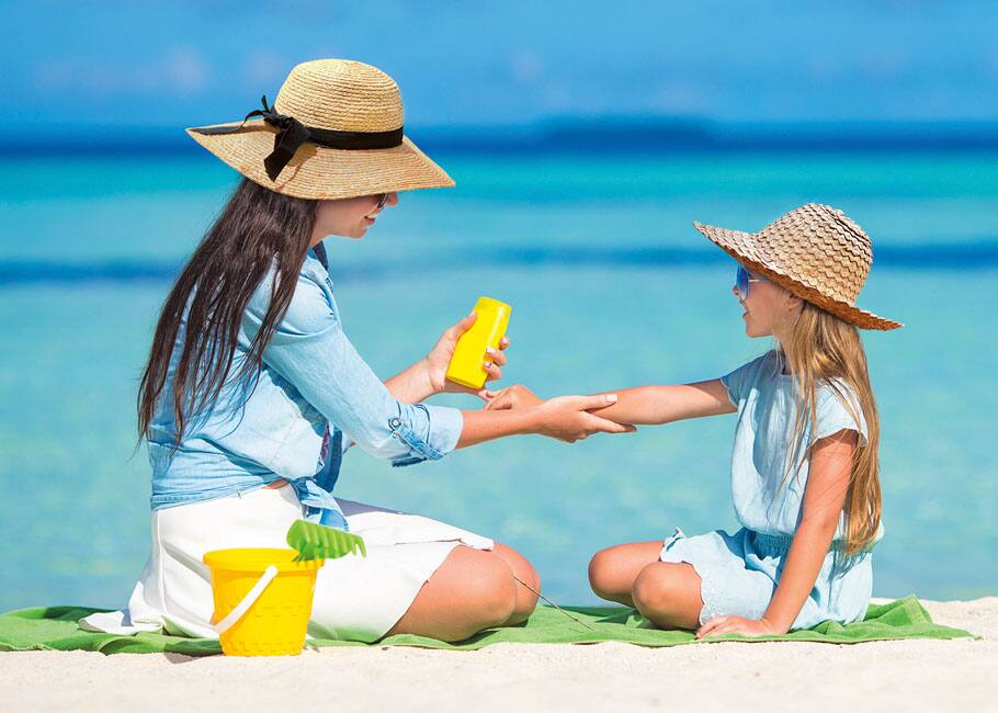 woman putting sunscreen on her kid by the beach