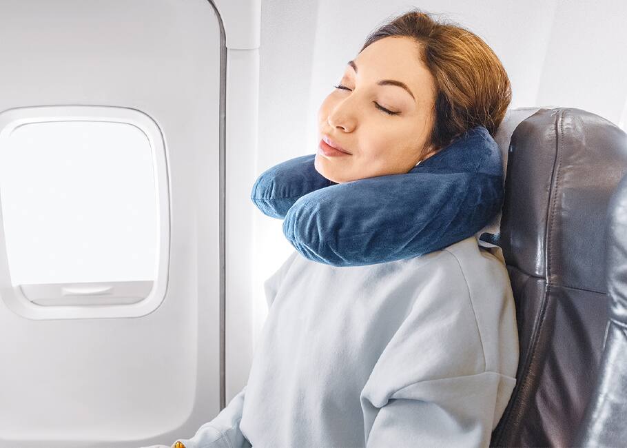 woman on an airplane sleeping with a neck pillow