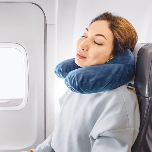 woman sleeping in an airplane with a neck pillow