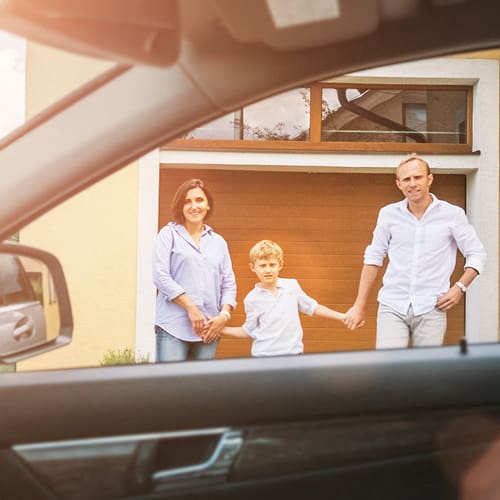 family holding hands outside a car