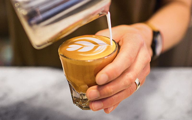 person pouring espresso into a glass