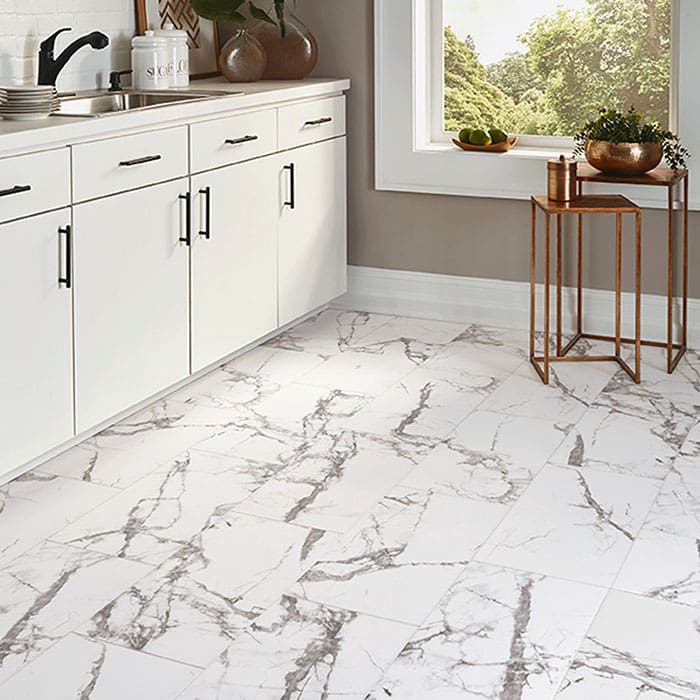 Smaller kitchen concept, with shellacked white cabinets, bright window and vinyl flooring in a gray and white marble pattern.