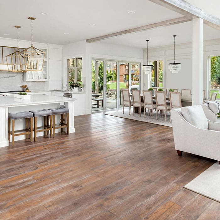 Large, open room concept connecting kitchen with dining and living area. Medium-dark, solid hardwood flooring covers entire area.