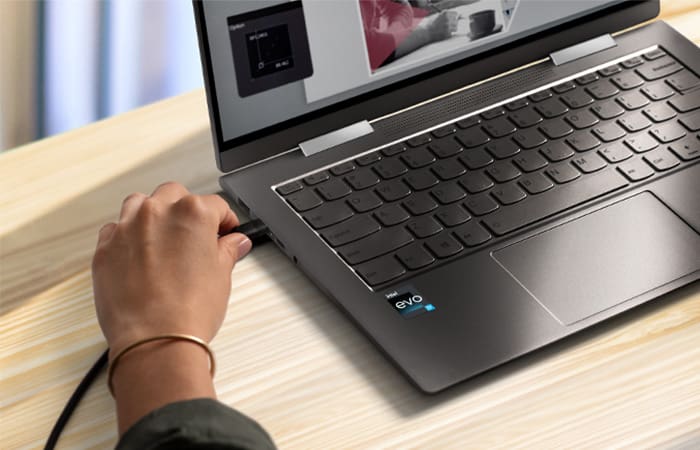 Persons hand demonstrating the removal of the charging cable from the side of a laptop