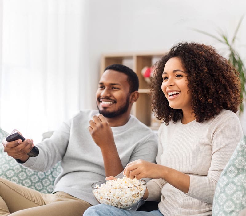 man and woman eating popcorn sitting on a couch