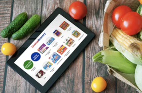 Tablet with grocery items next to fresh vegetables
