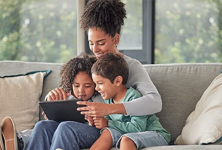 A family on the couch looking at a tablet.
